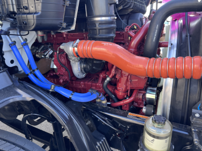 Mack AN64T engine bay showing orange intake pipe, red engine block, blue hoses, and black radiator supports.