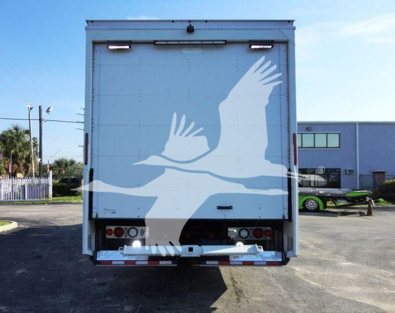 Rear view of a 2022 International MV rollback truck with a large white crane-like bird graphic on the tailgate.