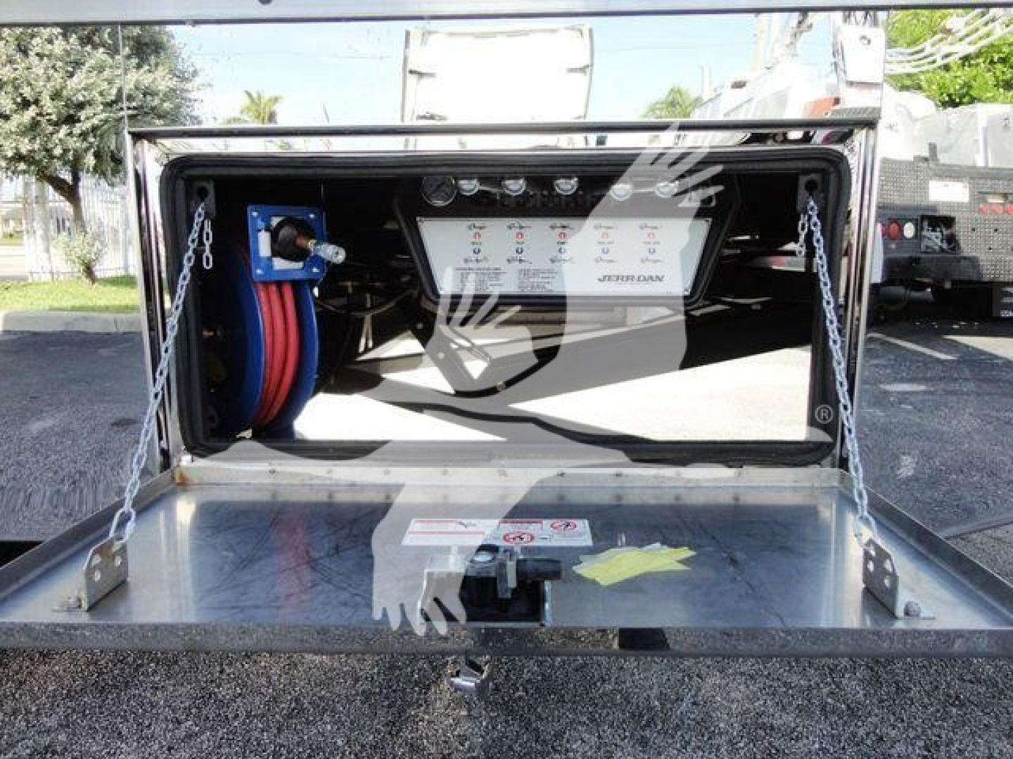 Image showing back end of 2022 International MV rollback truck with service panel, hoses, and control panel inside open storage compartment.