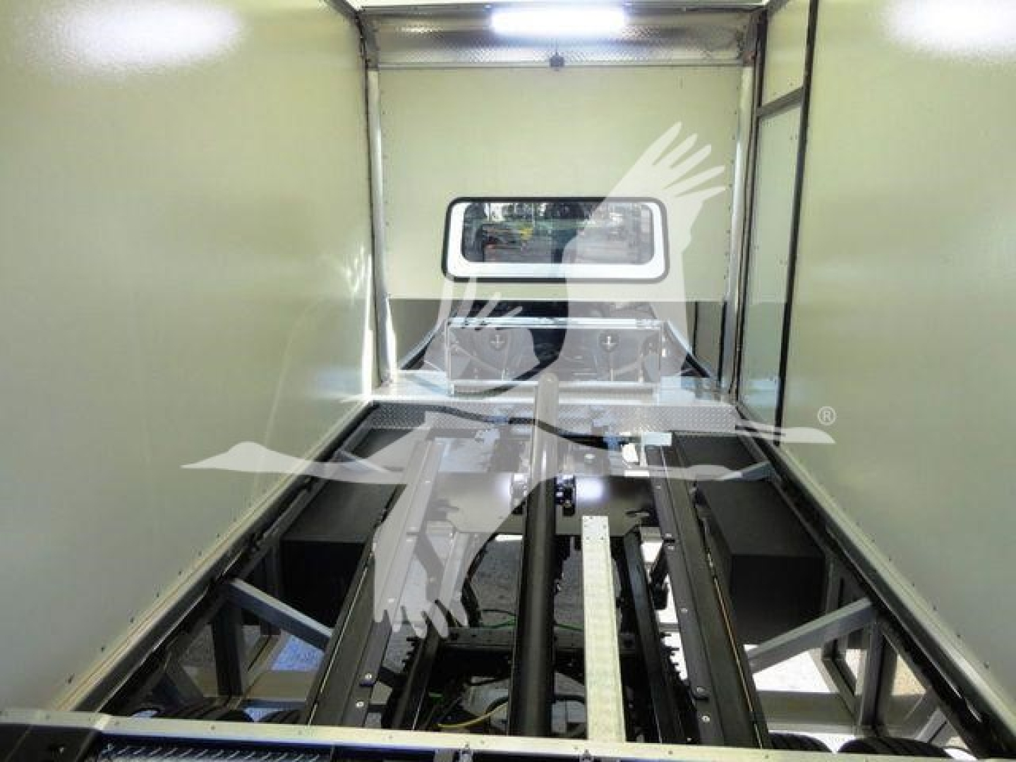 Truck bed interior showing metal rails and a windowed bulkhead at the far end.