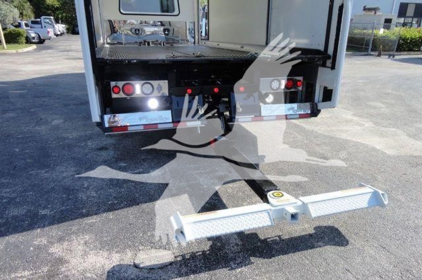 Back of 2022 International MV rollback truck showing bumper, hitch, and electrical connectors with a horizontal steel hitch receiver and reflective tape.