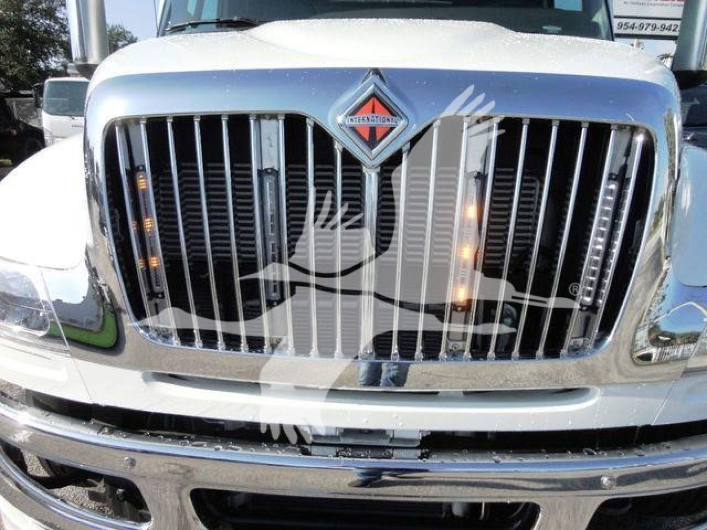 Front grille of a white 2022 International MV truck showing chrome vertical grille bars, International badge, and reflective chrome bumper.