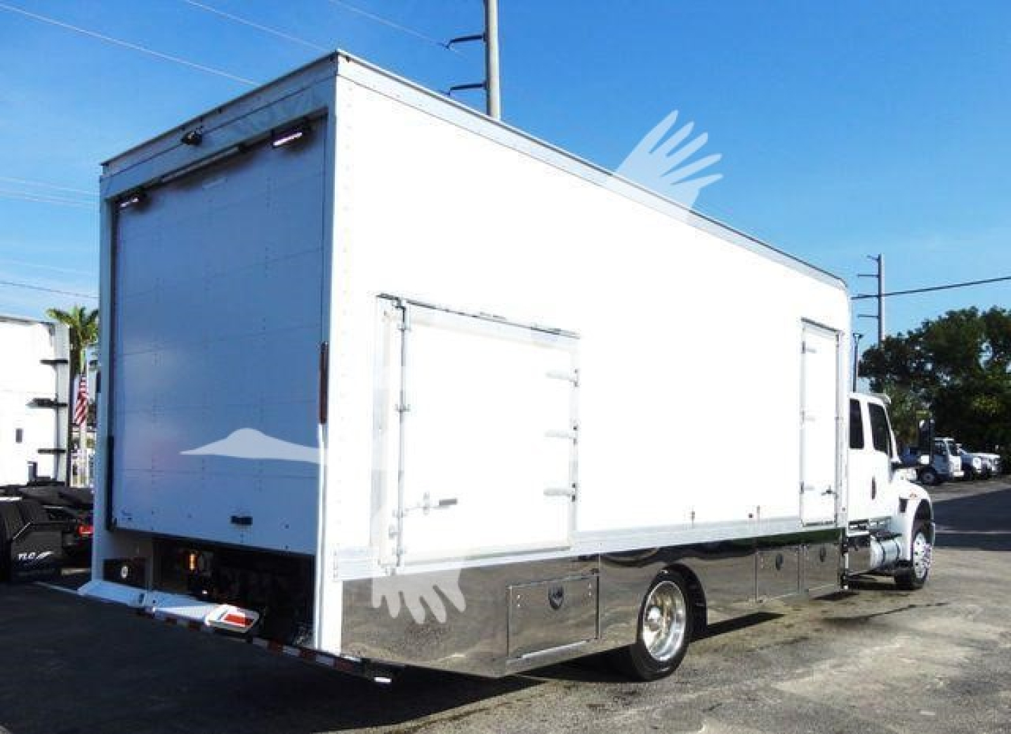 Box truck side/back view showing white cargo box with rear doors on International MV rollback truck.
