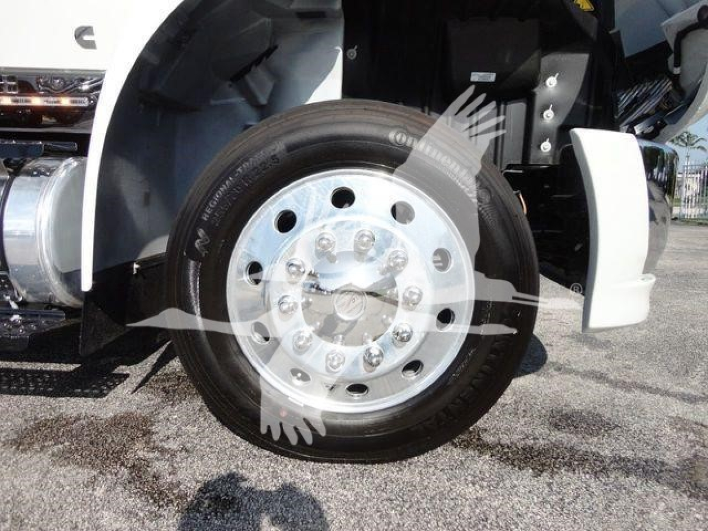 Front wheel and fender of a white International MV truck showing wheel hub and tire.