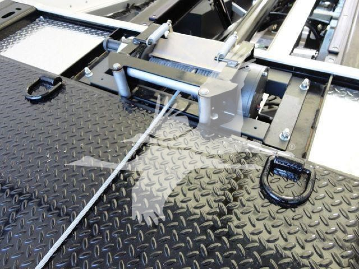 Truck equipment in-service showing hydraulic line and mechanism on a diamond-plate surface of an International MV rollback unit.