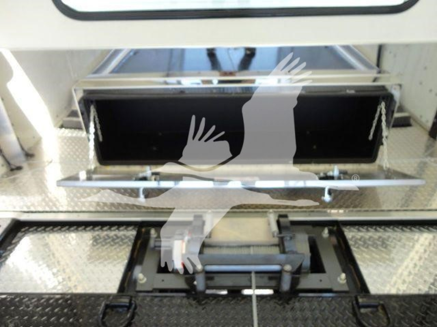 International MV rollback truck component showing open storage compartment with black interior and metal mounting hardware.