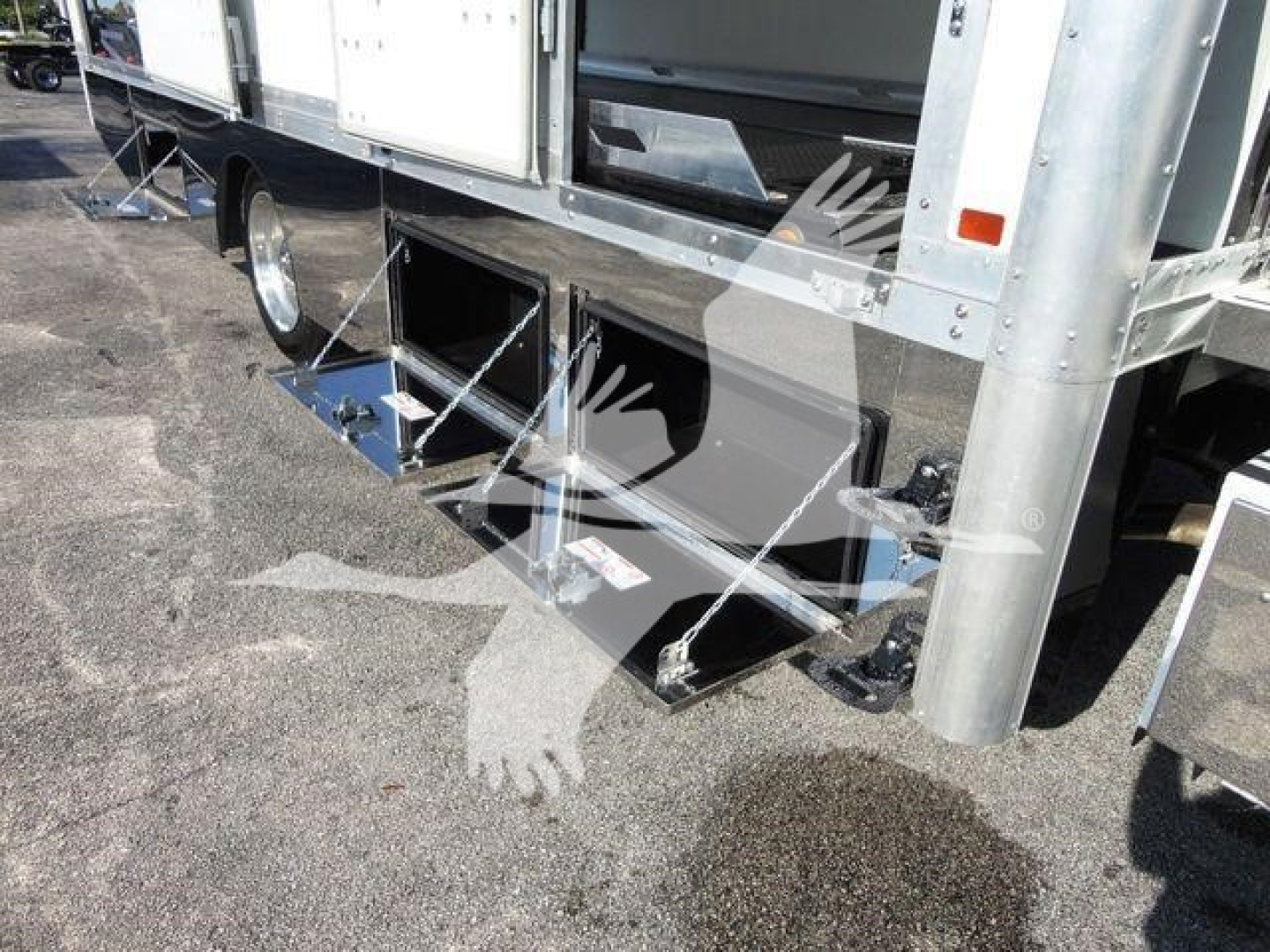 Truck rollback body with underbody storage compartments and step access showing metal framework and wheels.