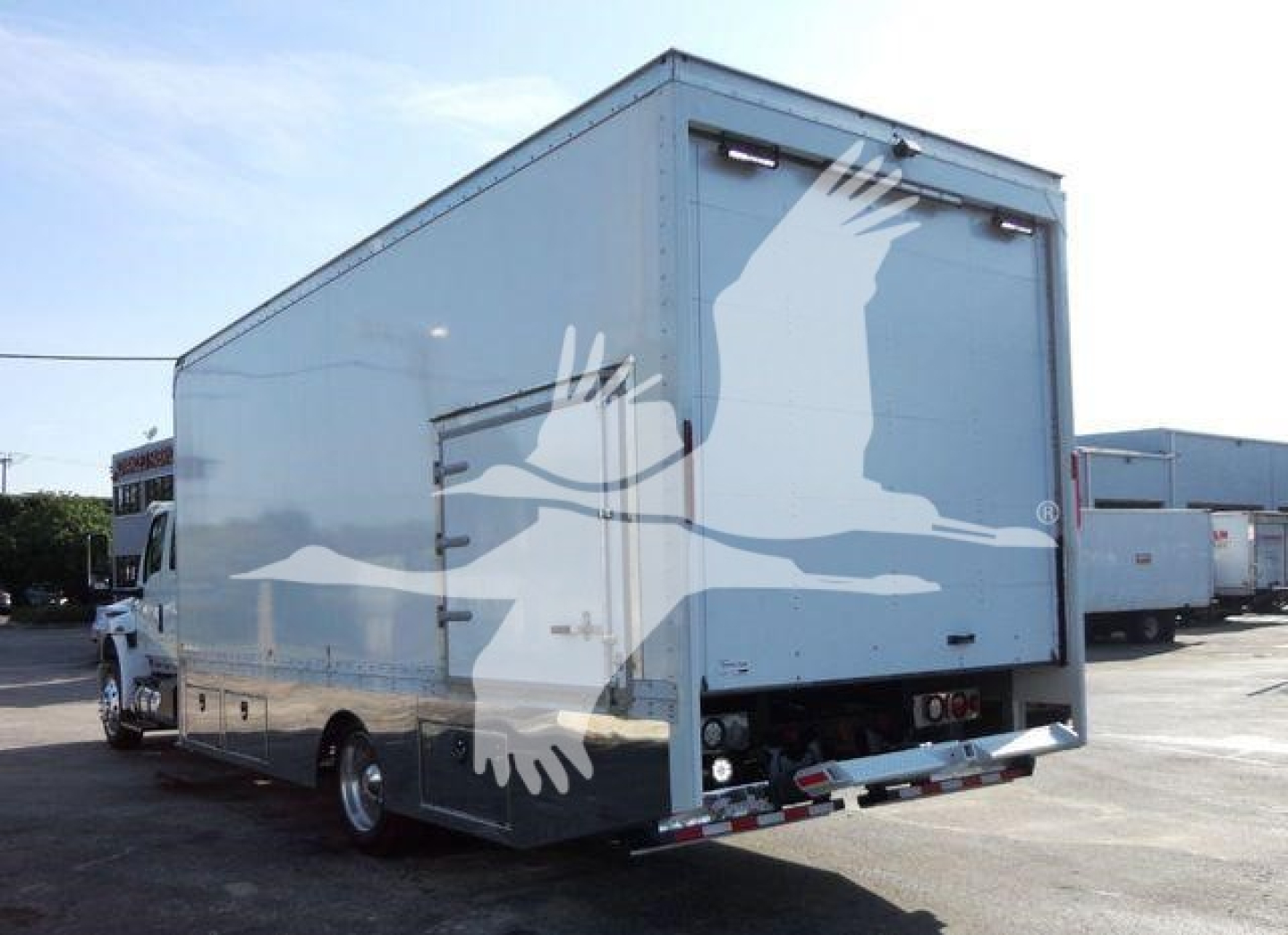 Box truck back and side view showing large white bird graphic on cargo box with rear doors closed and platform bumper.