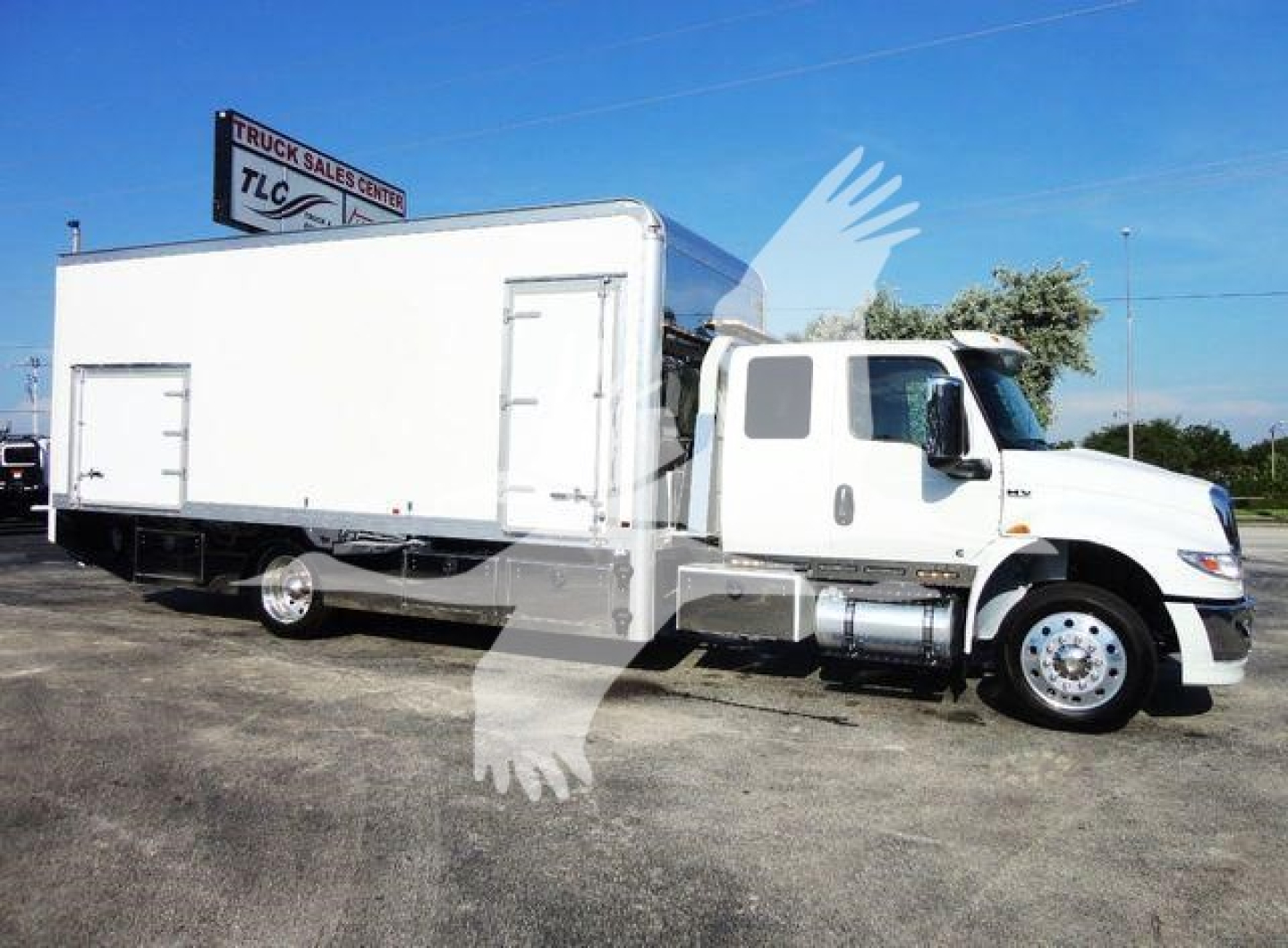 Truck image showing a white 2022 International MV rollback/rotary with a large cargo box and cab in front, side view.