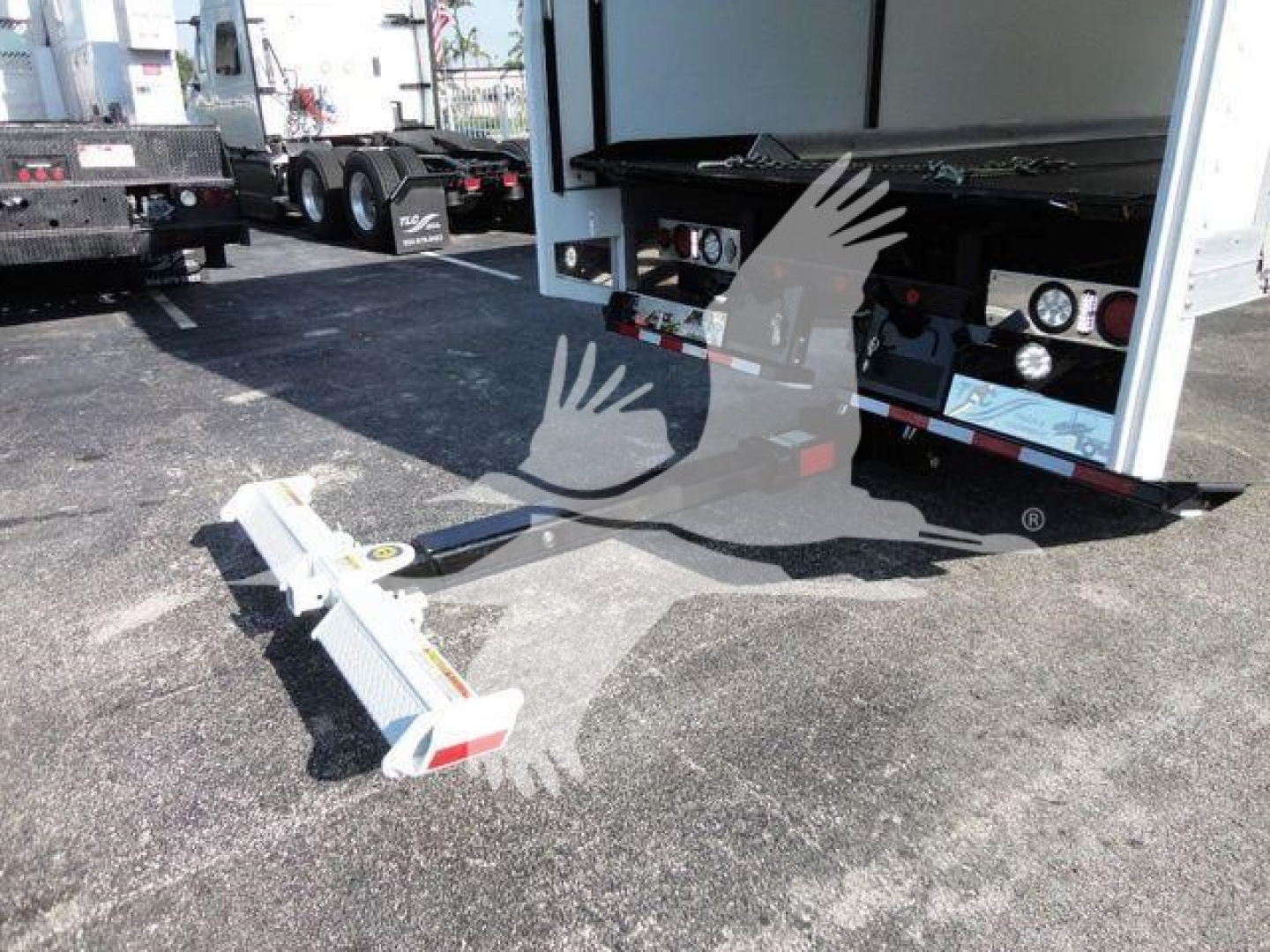 Truck rollback tow bar and rear of 2022 International MV trailer in a lot showing the hitch and rear bumper with fuel gauges and hoses.