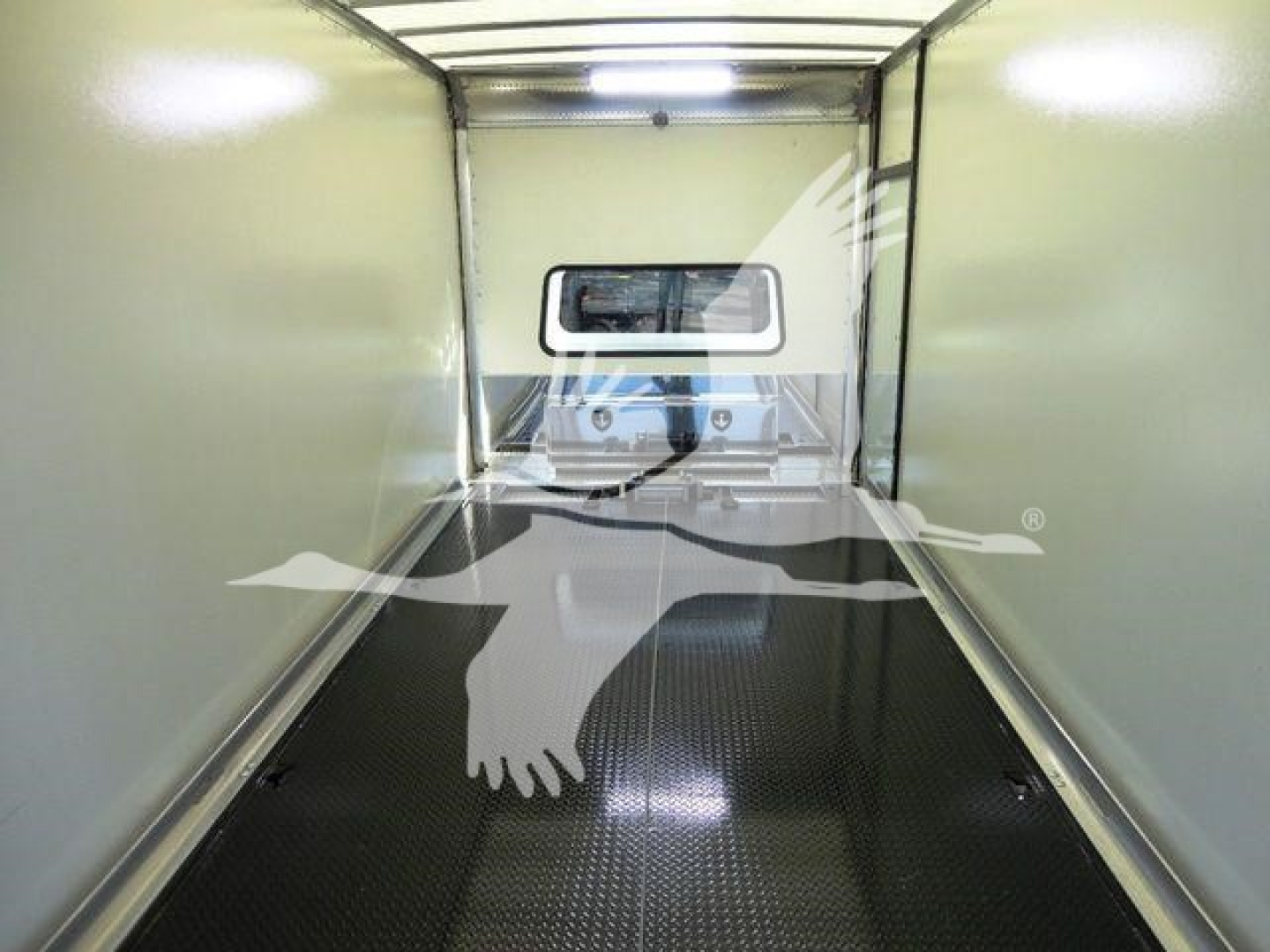 Tractor-trailer interior showing empty cargo area with window at far end and textured floor.