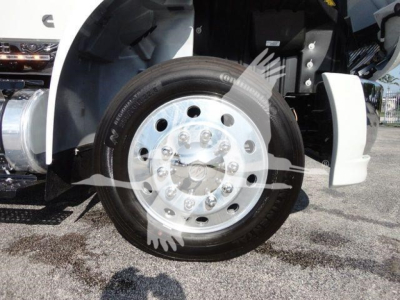 Front wheel and fender of a white International MV truck showing wheel hub and tire.