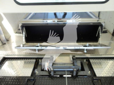 International MV rollback truck component showing open storage compartment with black interior and metal mounting hardware.
