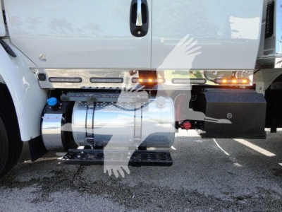 Truck side view showing chrome fuel tank, steps, and amber marker lights on International MV rollback truck.