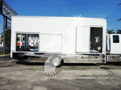 Truck body in service bay showing a white boombed utility truck with side compartments and an open rear door.