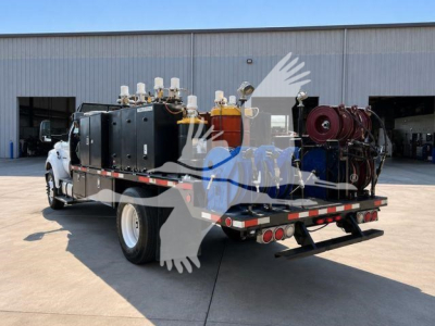 Flatbed tow truck with a pump system and multiple mounted gas or air tanks on the bed, rear view showing side cabinets and hoses.