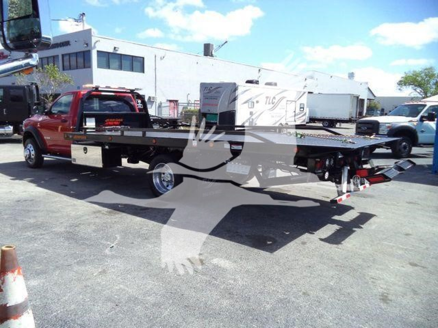 Ram 5500 rollback tow truck with flatbed, red cab, side view showing long flatbed and towing equipment.