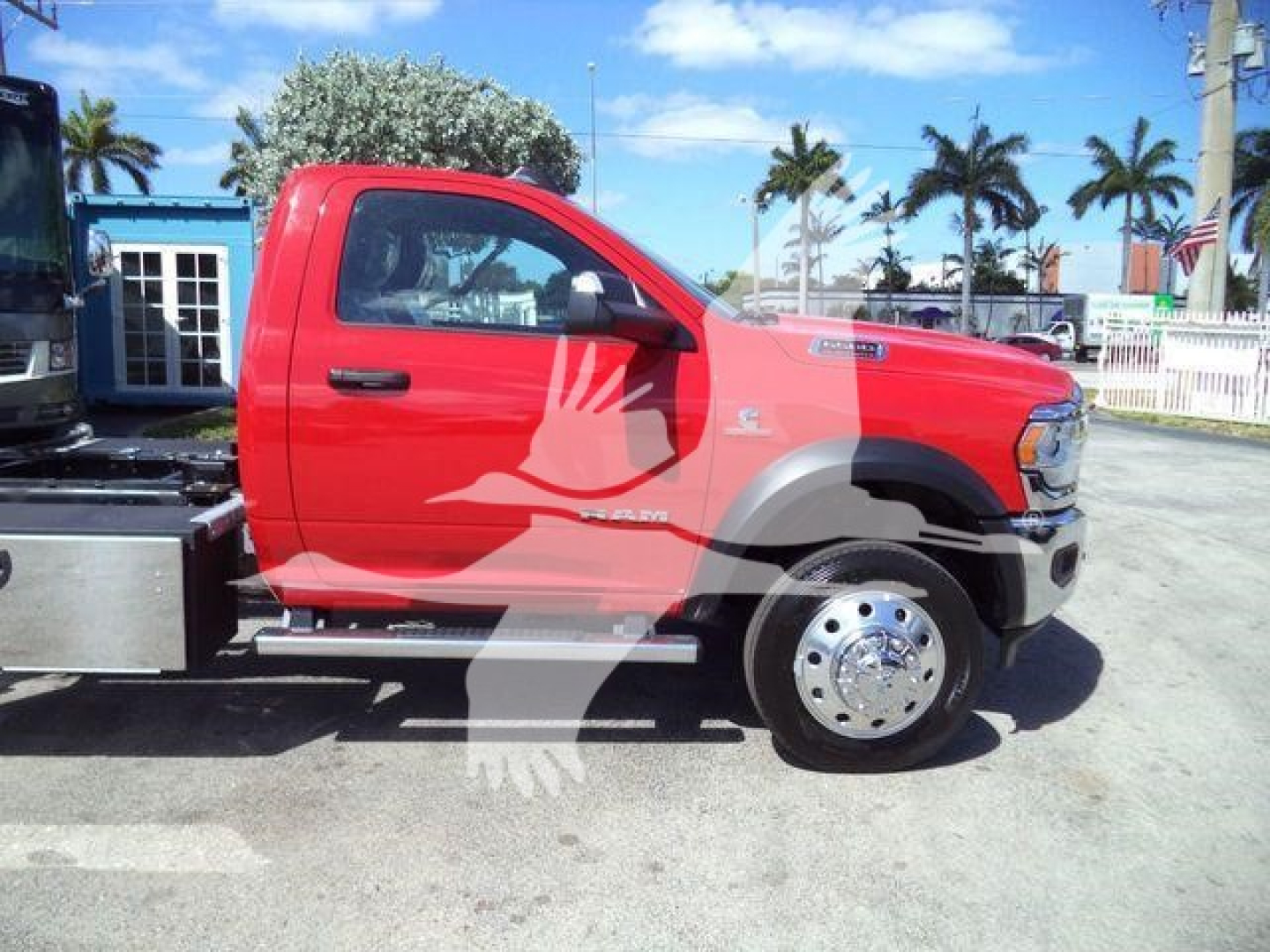 Ram 5500 rollback truck side view showing red cab, chrome hubcap, and side step; branding on door and fender.