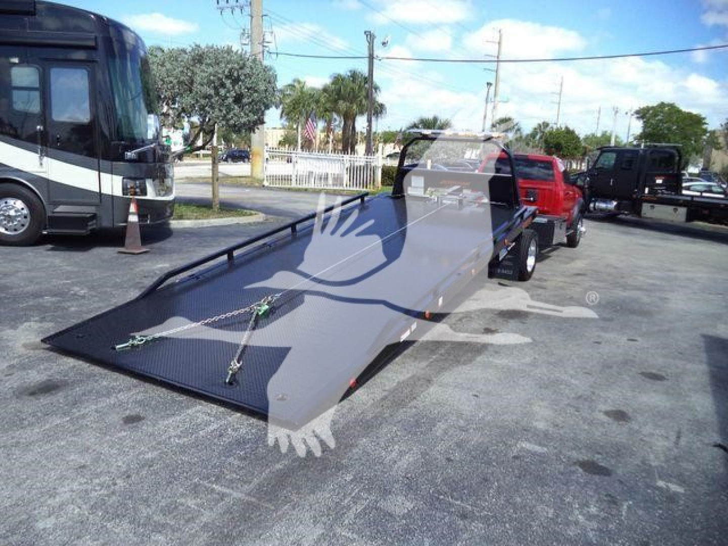 Ram 5500 Rollback flatbed with ramp and trailer hitch, showing loading deck and tie-down straps.