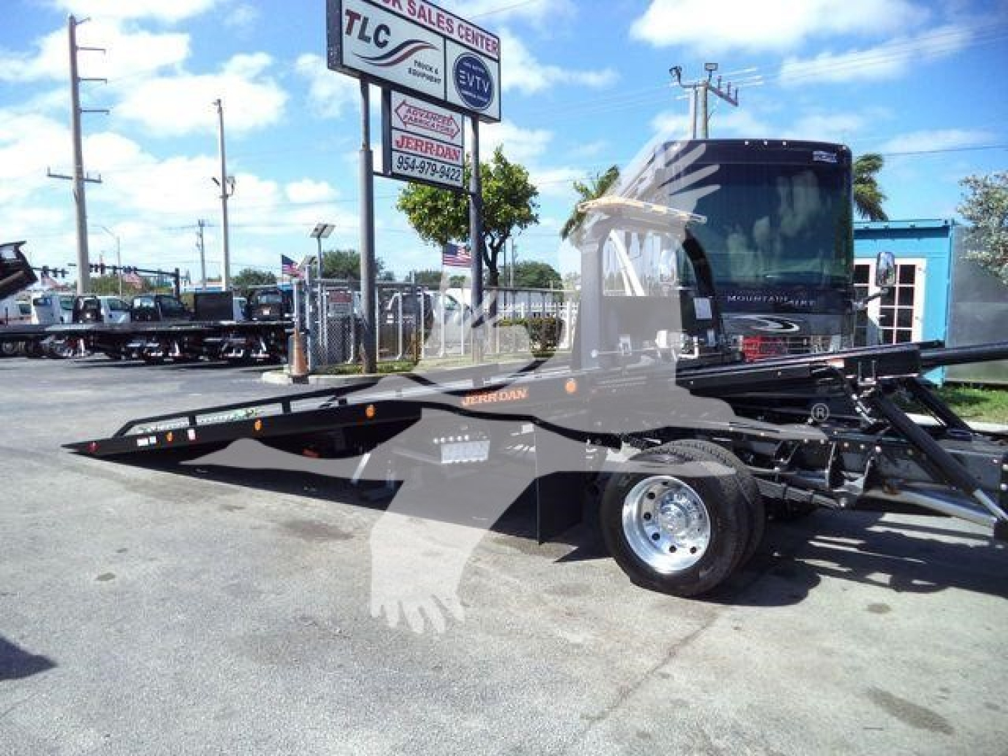 Tow truck rollback bed mounted on Ram 5500 SLT chassis with hydraulic tilt/slide bed and black cab in dealership lot.