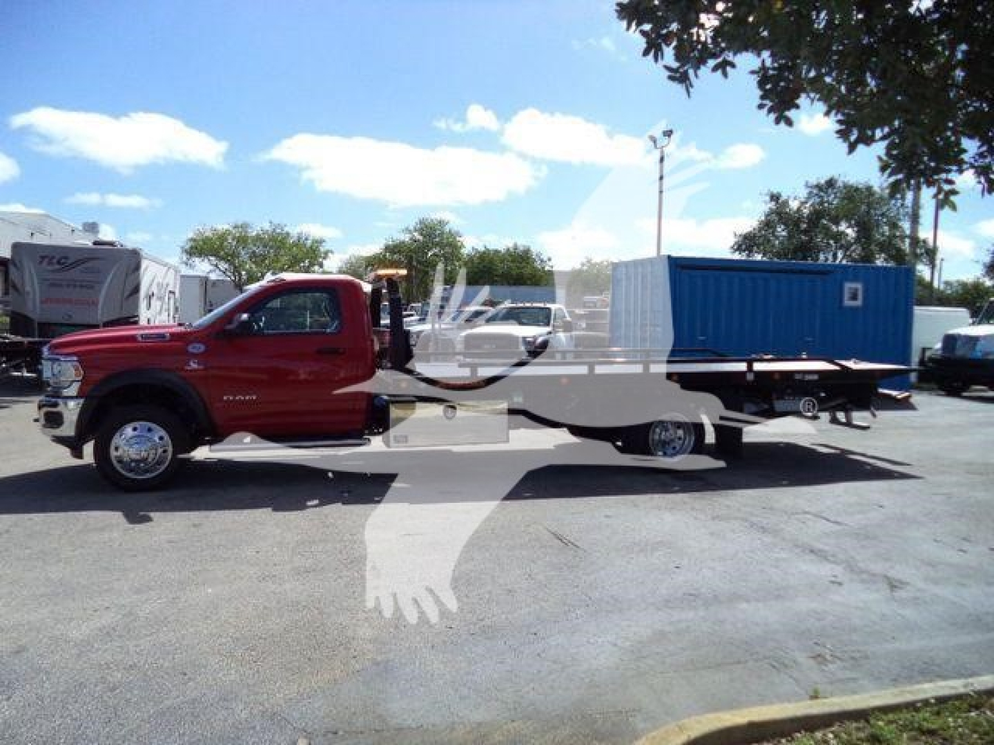 Ram 5500 rollback truck with flatbed and blue utility container in lot showing cab and chassis
