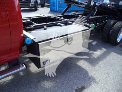 Ram 5500 rollback truck chassis showing a rectangular fuel or battery box under the cab with a blue cap and a black metal frame nearby.