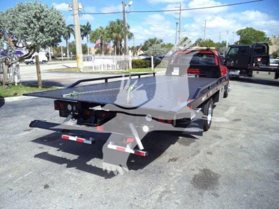 Ram 5500 rollback flatbed truck in outdoor lot, rear view showing steel flatbed and towing equipment.