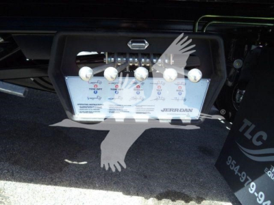 Rear view of a Ram 5500 rollback body showing a license plate area with multiple chrome pins and a plate; Jerr-Dan logo visible; some text on the plate and a TLC sign nearby.