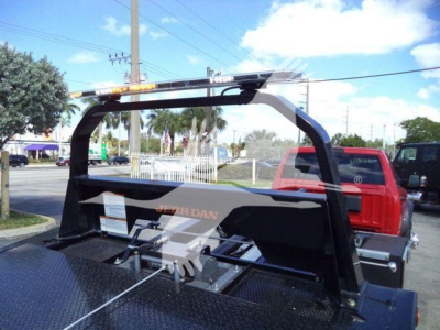 Ram 5500 rollback truck bed with integrated towing winch and hydraulic hoist, rear view showing flatbed with steel diamond plate and rollover protection arch.