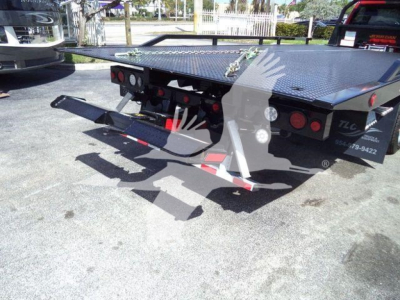 Ram 5500 rollback truck bed showing rear with towing arms and platform, OEM lights, and torque plate.
