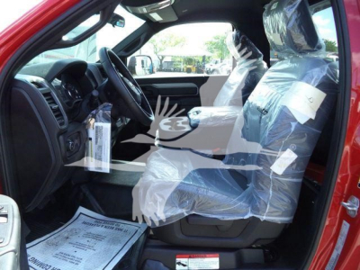 Ram 5500 SLT cab interior view with front seats wrapped in plastic, steering wheel and dashboard visible, driver-side door open.