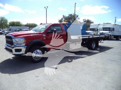 Ram 5500SLT rollback truck with flatbed in red color, side view showing dual rear axle and blue container on bed.