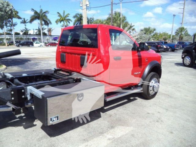 Ram 5500 chassis cab with rollback bed, red cab, fuel tank/box on side, rear view showing wheel and cab profile.