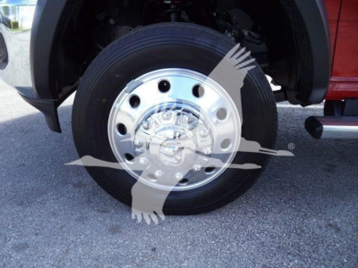 Wheel close-up on a Ram 5500 truck showing a polished chrome hubcap and black tire, undercarriage visible, fender above.