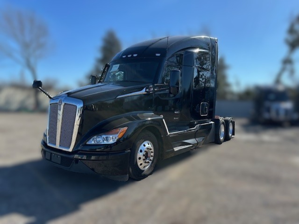 Truck cab front-left view showing 2022 KW T680 sleeper with black paint and chrome grille, daytime; visible wheels and mirrors.