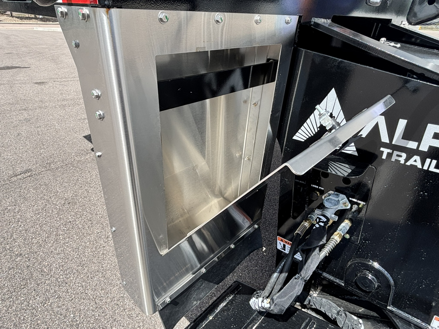HDGC-E 48' lowboy trailer photo showing a metal toolbox/compartment with riveted aluminum skin and hydraulic hoses near the hitch area.