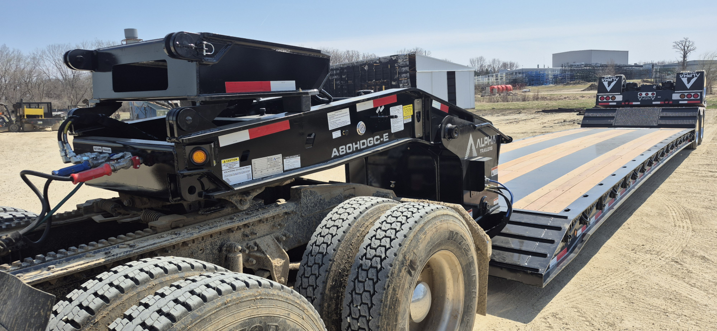 Trailer with extendable lowboy deck showing hydraulic detachment and dual drop extendable section, heavy-duty tires, and wiring harness; Alph a HDGC-E model label visible.