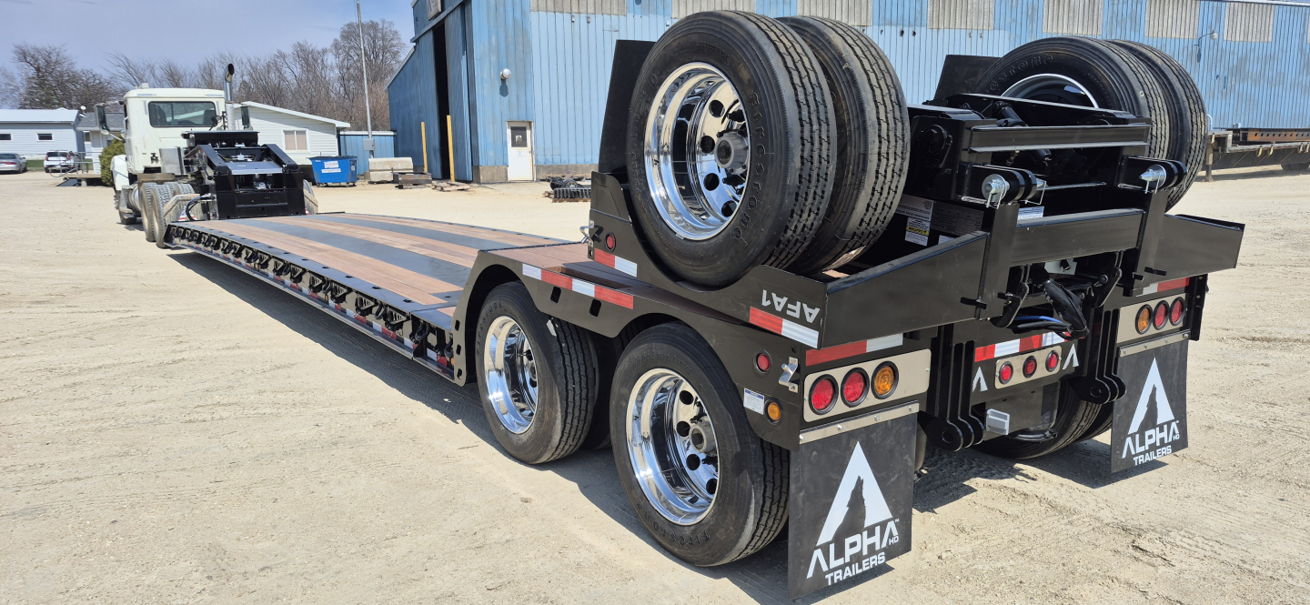 Alpha trailers HDGC-E lowboy showing extendable double drop with hydraulic detachment. Tandem rear axles, spare tires mounted on gooseneck area, rear mudflaps with Alpha logo.