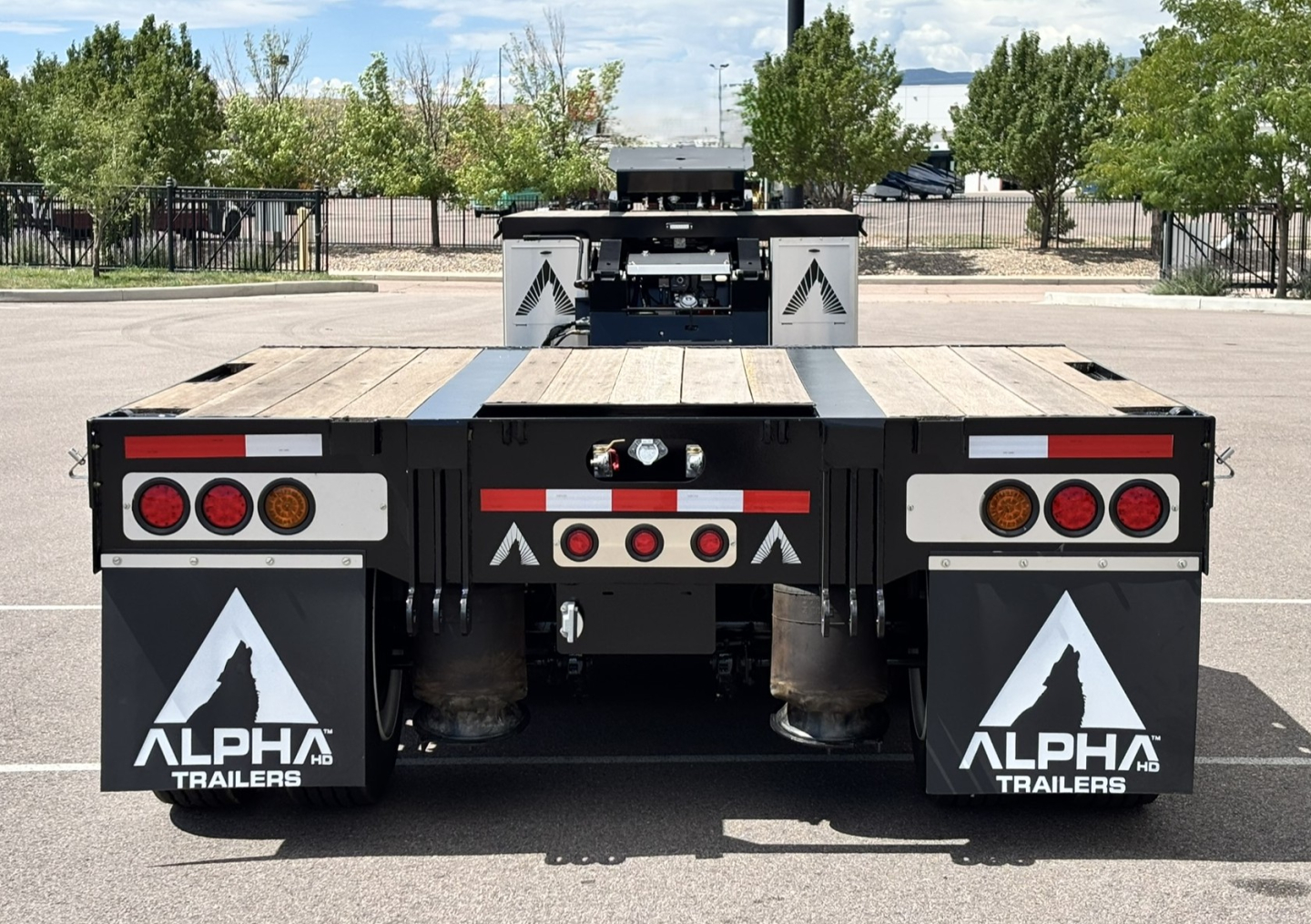 Rear view of Alpha Trailers 2027 A80 HDGC-E lowboy trailer with dual pneumatic mud flaps, taillights, and deck extension.