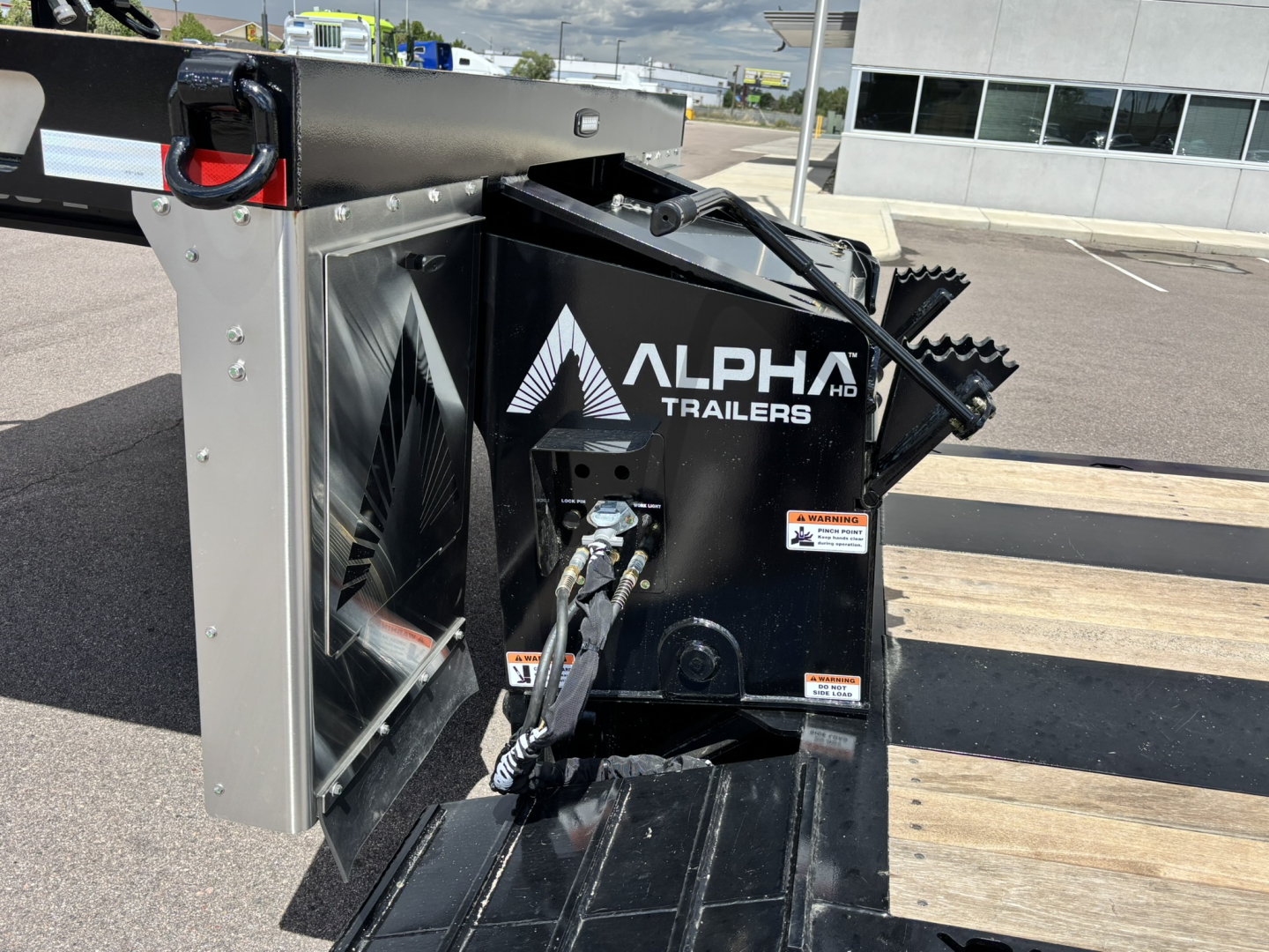 Alpha Trailers A80 HDGC-E lowboy trailer hitch unit with hydraulic detach and double drop extendable feature in black with stacked wood deck and safety chains visible.