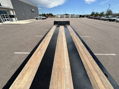 Trailer deck view of a 48' lowboy with wood and black steel decking, front detatchable kingpin area, long extendable hyd detach double drop extendable trailer.