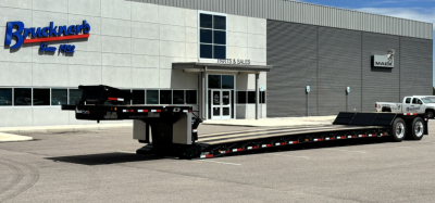 Lowboy trailer in front of sales building showing long hyd detach double drop extendable flatbed with extendable deck and dual rear axles.