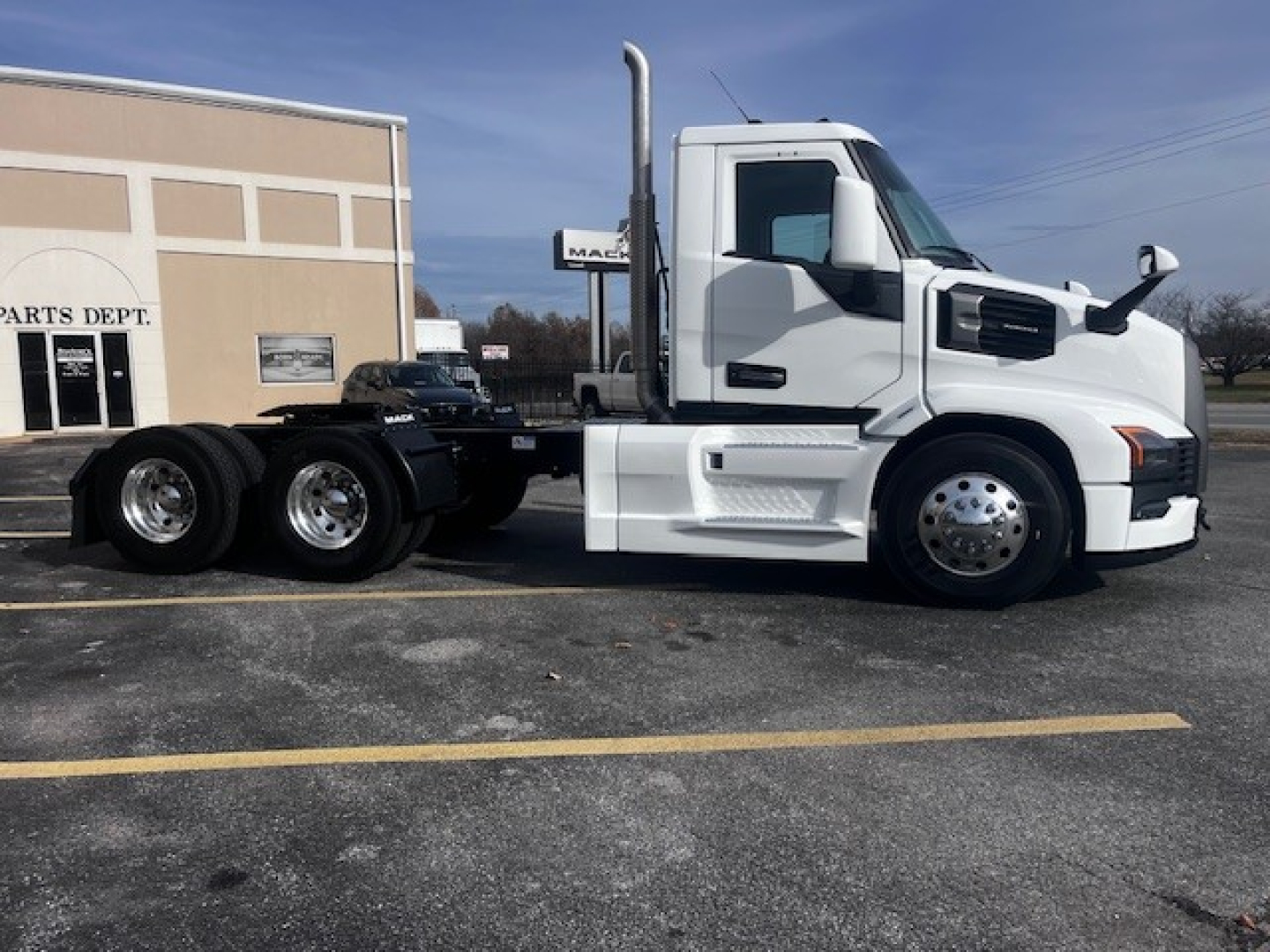 Truck side view showing a white 2026 Mack PR64T conventional daycab with a long wheelbase, chassis, and dual rear axles.