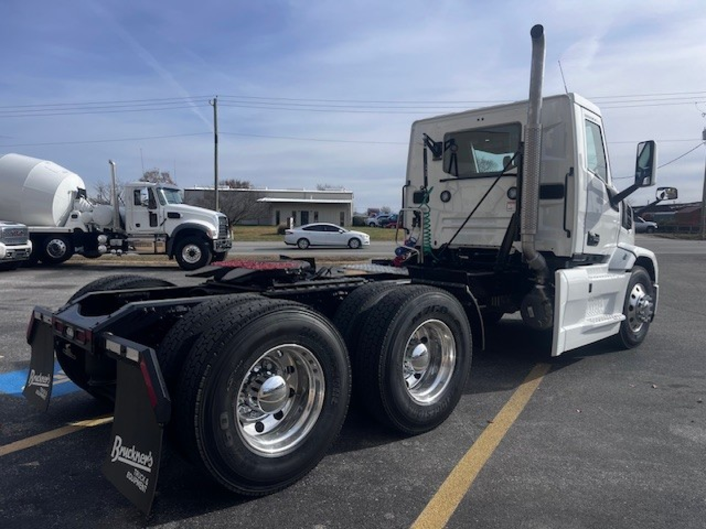 Mack PR64T truck cab and chassis in front view showing rear dual wheels, fuel tanks, mirrors, and exhaust stack.