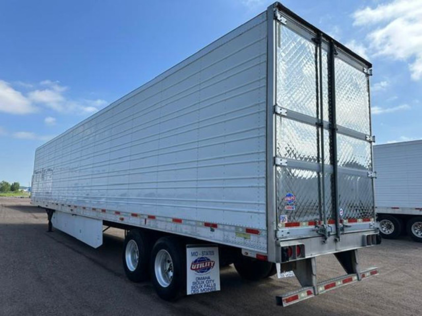 Trailer side and rear showing aluminum refrigerated trailer with dual rear doors and diamond plate at the back.