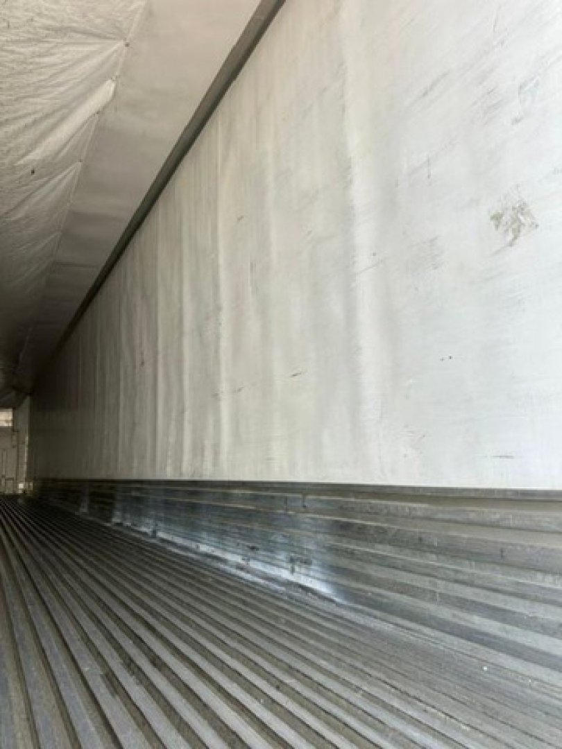 Reefer trailer interior showing insulated side walls and ribbed metal floor.
