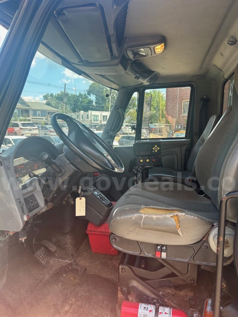 Cab interior of a 2007 International 7400 dump truck showing steering wheel, dashboard, and worn driver's seat.