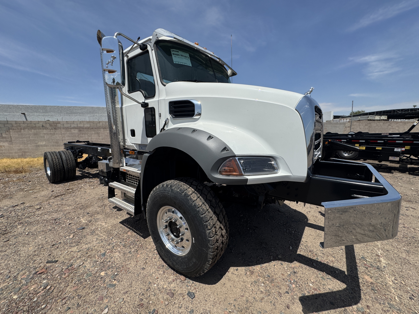 Mack GR44B cab and chassis truck side view showing front wheel, white hood, metal front bumper/dump chest area, and utility side mirror.