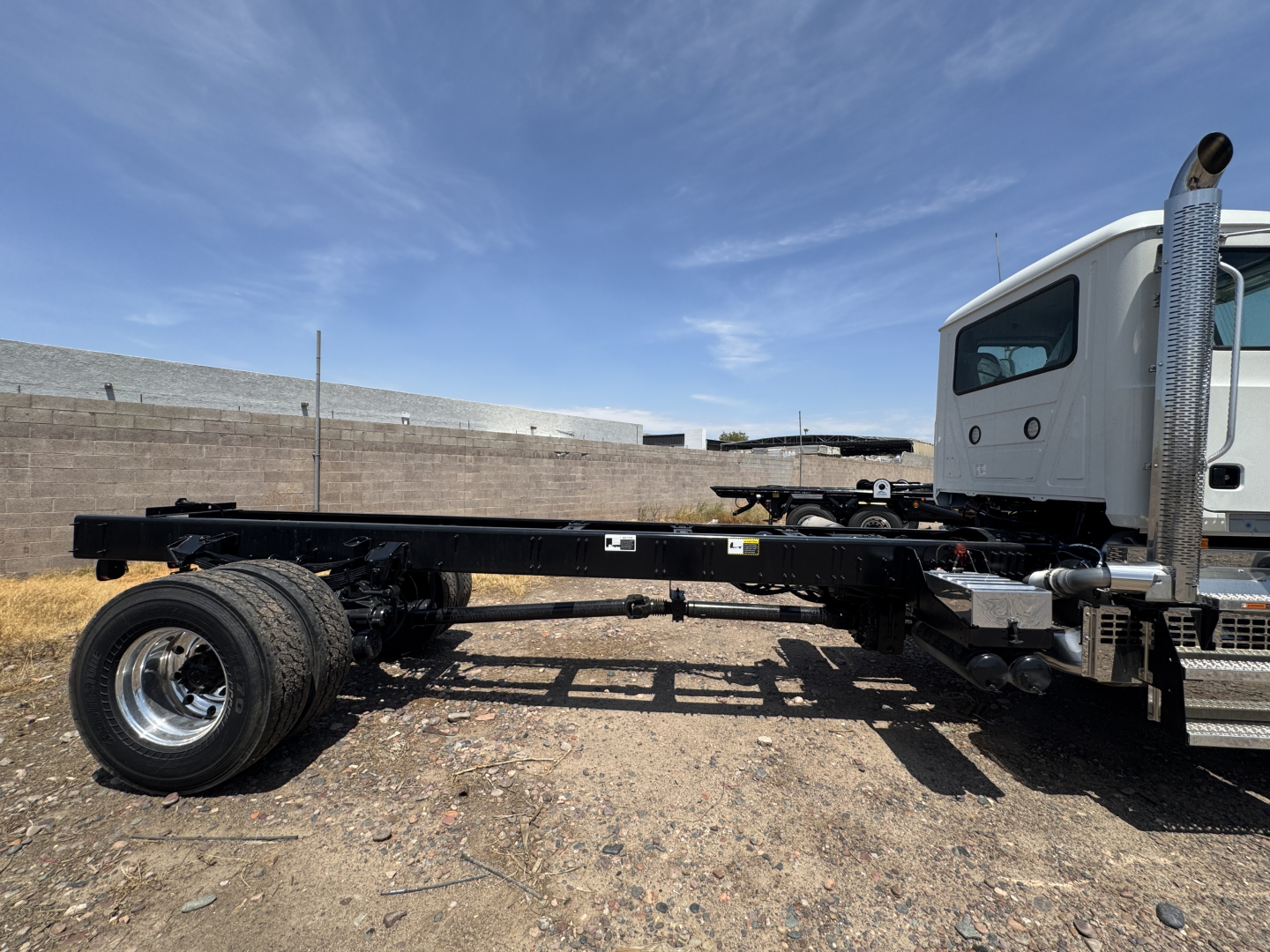Mack GR44B cab and chassis truck frame with single rear axle and white cab showing VIN 1M2GR4CC1VM001073 on a gravel lot.