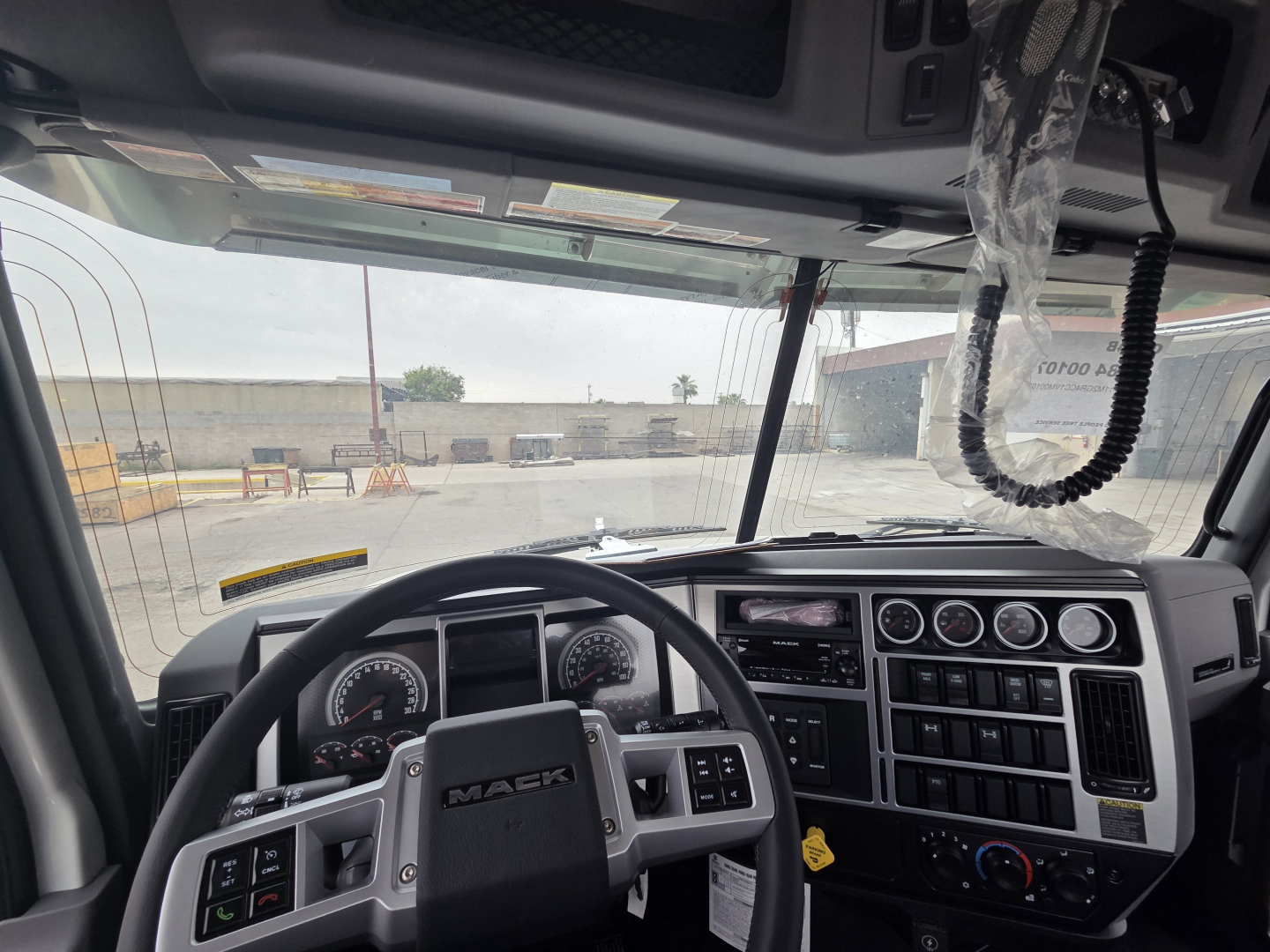Cab interior of a Mack truck showing steering wheel, dashboard gauges, and control panel.
